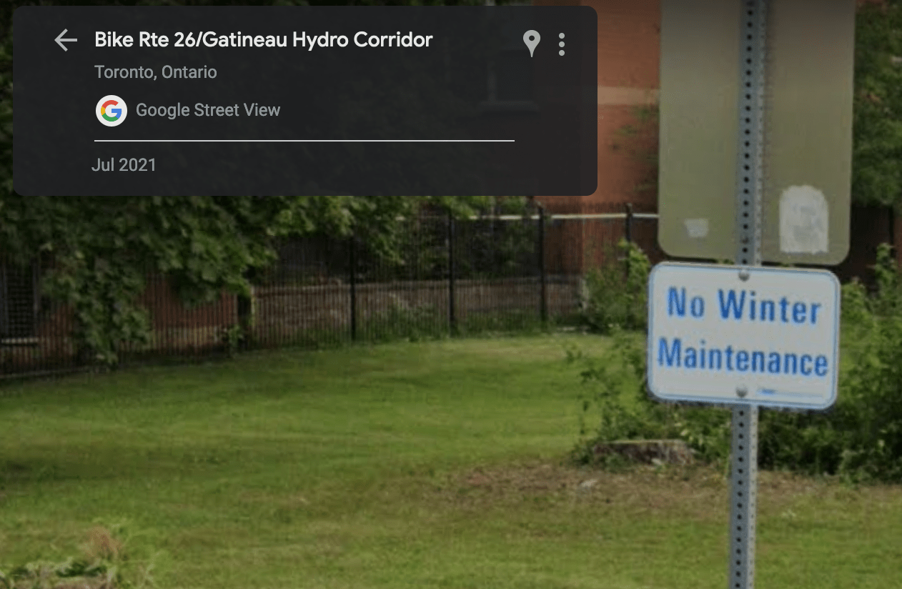 Screenshot of Google Street View showing a trail sign that reads "No Winter Maintenance". There is a fence in the background.